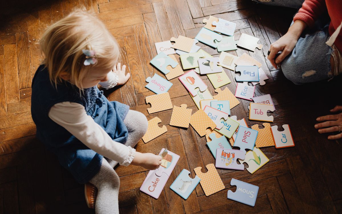 niña juega en el suelo con puzzle